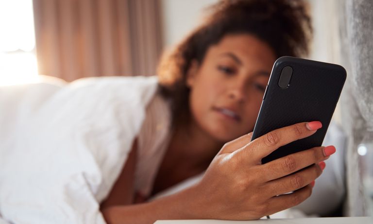 young woman checks mobile phone from bed 768 Tricks used to get rid of mobile phone addiction.